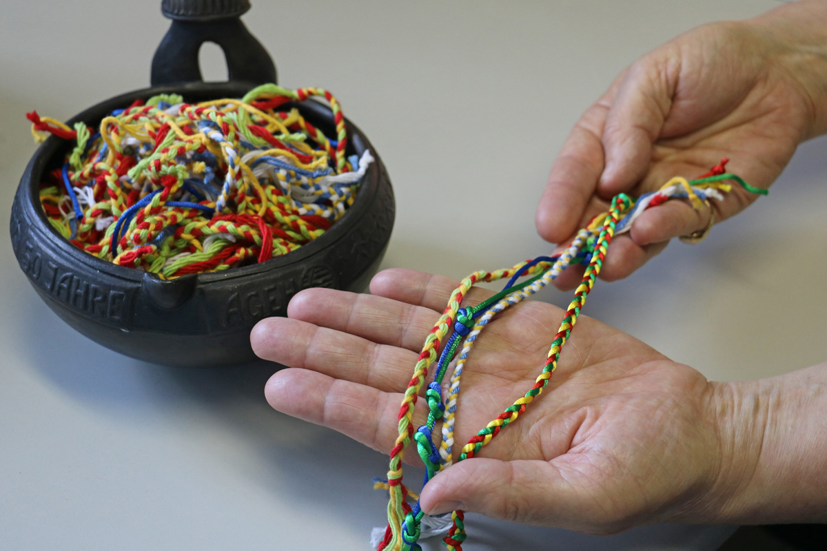 "Vor Ausreise gebe ich Fachkräften eines dieser Bändchen, das Kinder in einem 'unserer' Projekte geflochten haben, mit den Worten. „Die Zusammenarbeit ist für eine bestimmte Zeit geknüpft: Wir beginnen als einzelne Farbstränge, verknoten uns miteinander in der verbindlichen Vertragsabsprache, in der Zusammenarbeit erst werden wir bunt und stark!"