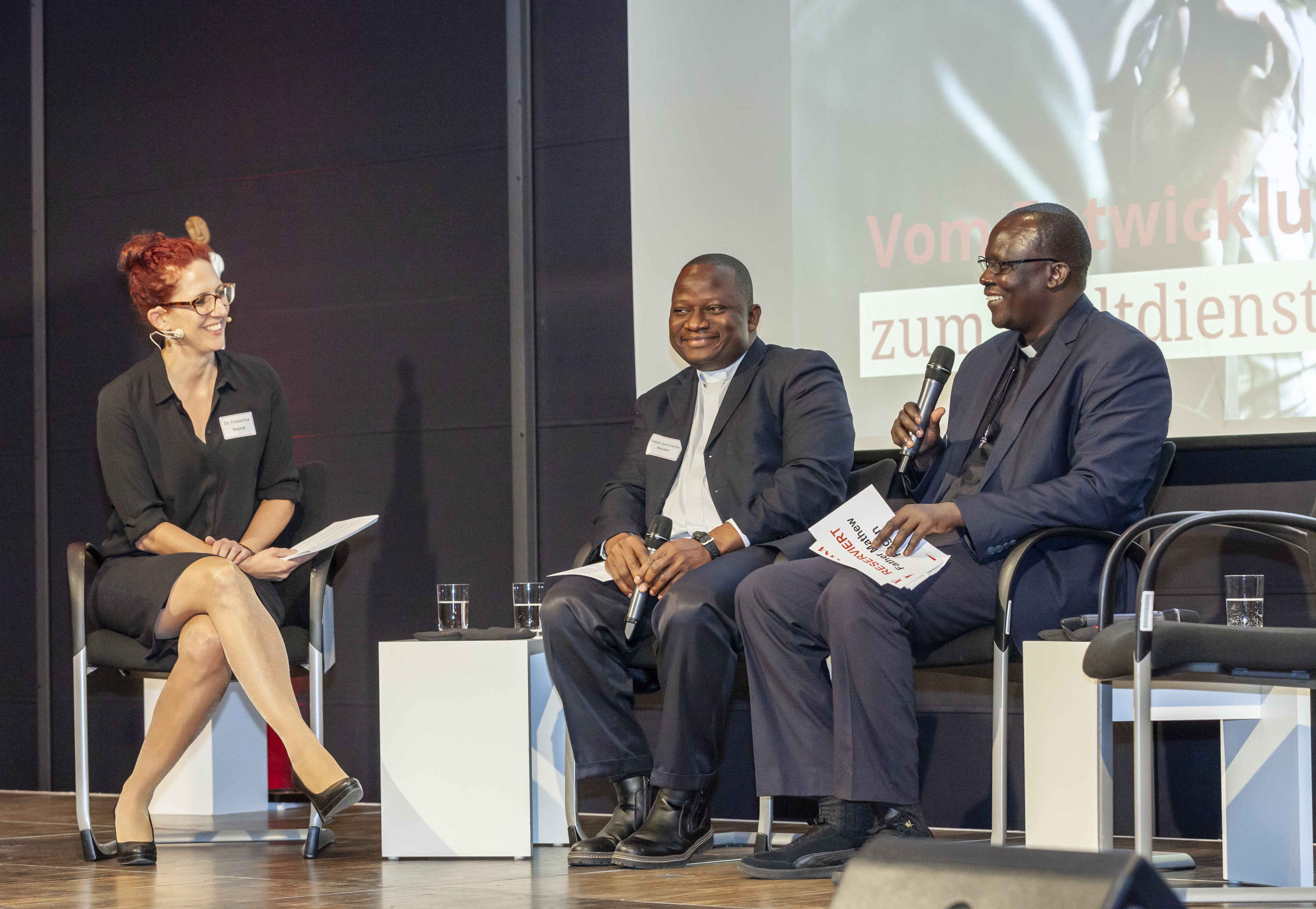 Father Sumo-Varfee Molubah (AGIAMONDO-Partner Liberia) und Father Dr. Mathew Pagan ‎‎(AGIAMONDO-Partner Südsudan) im Gespräch mit Moderatorin Dr. Friederike Repnik ‎‎(AGIAMONDO)‎