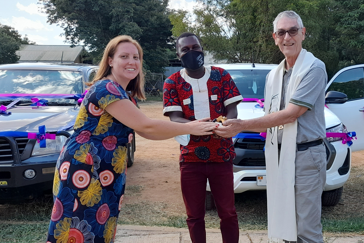 ZFD-Fachkraft Patricia Henning übergibt nach der Segnung der Fahrzeuge die Autoschlüssel an Michael Ochan, den Koordinator des Büros für Gerechtigkeit und Frieden sowie Bischof Filippi (von links).
