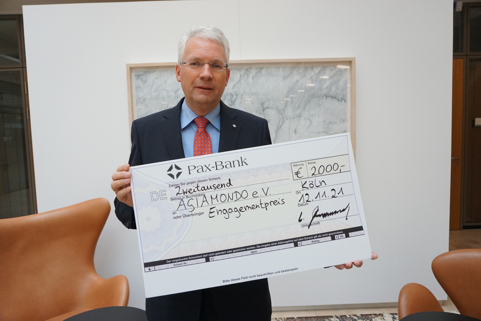 Wolfgang Altenrath, Regionaldirektor Köln der Pax-Bank eG, präsentiert den Scheck über 2.000 Euro Preisgeld. 