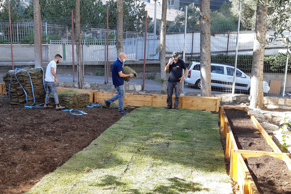 Klienten verlegen den Rollrasen für den offenen Treffpunkt neben den Hochbeeten.