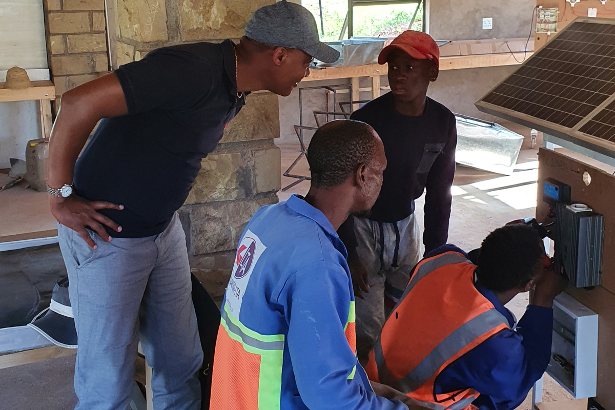 Auszubildende des TVET-Zentrums zeigen die Montage von Solarmodulen in ihrer Werkstatt.
