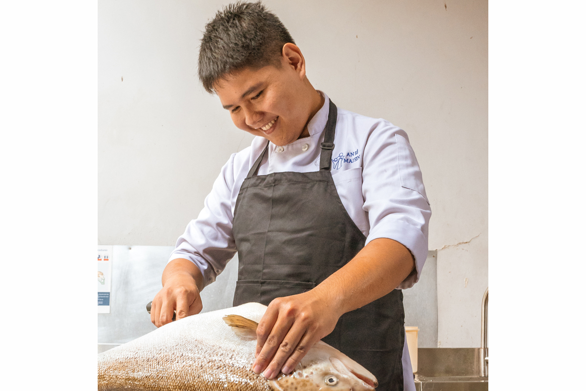 Nguyễn Hữu Tài nimmt in seiner Auszubildung zum Koch einen Lachs aus, um daraus gebratenes Lachssteak mit Limetten-Weißwein-Sauce, Spinat und Kartoffelgratin zuzubereiten.