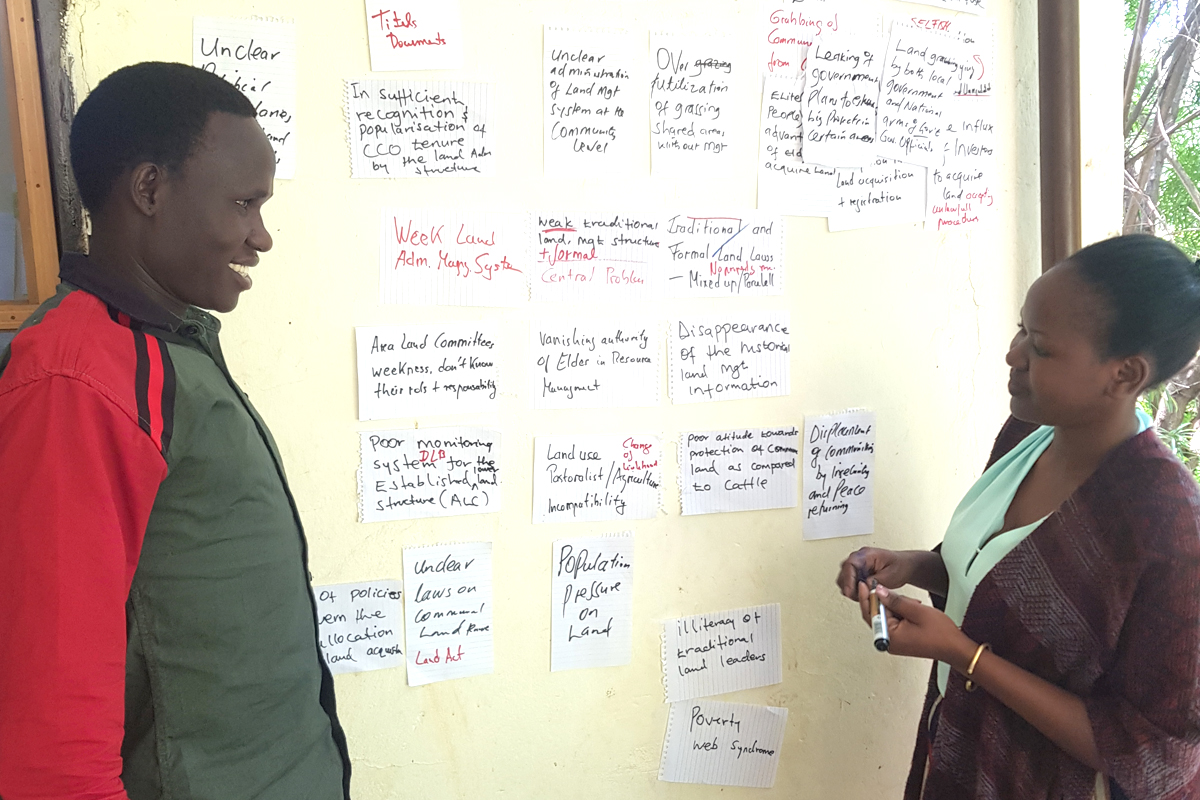 Abbo Fiona und Longole Faustine (von links), Mitarbeiter*innen des Land Desk, entwickeln eine Darstellung zum Thema Landproblematik.