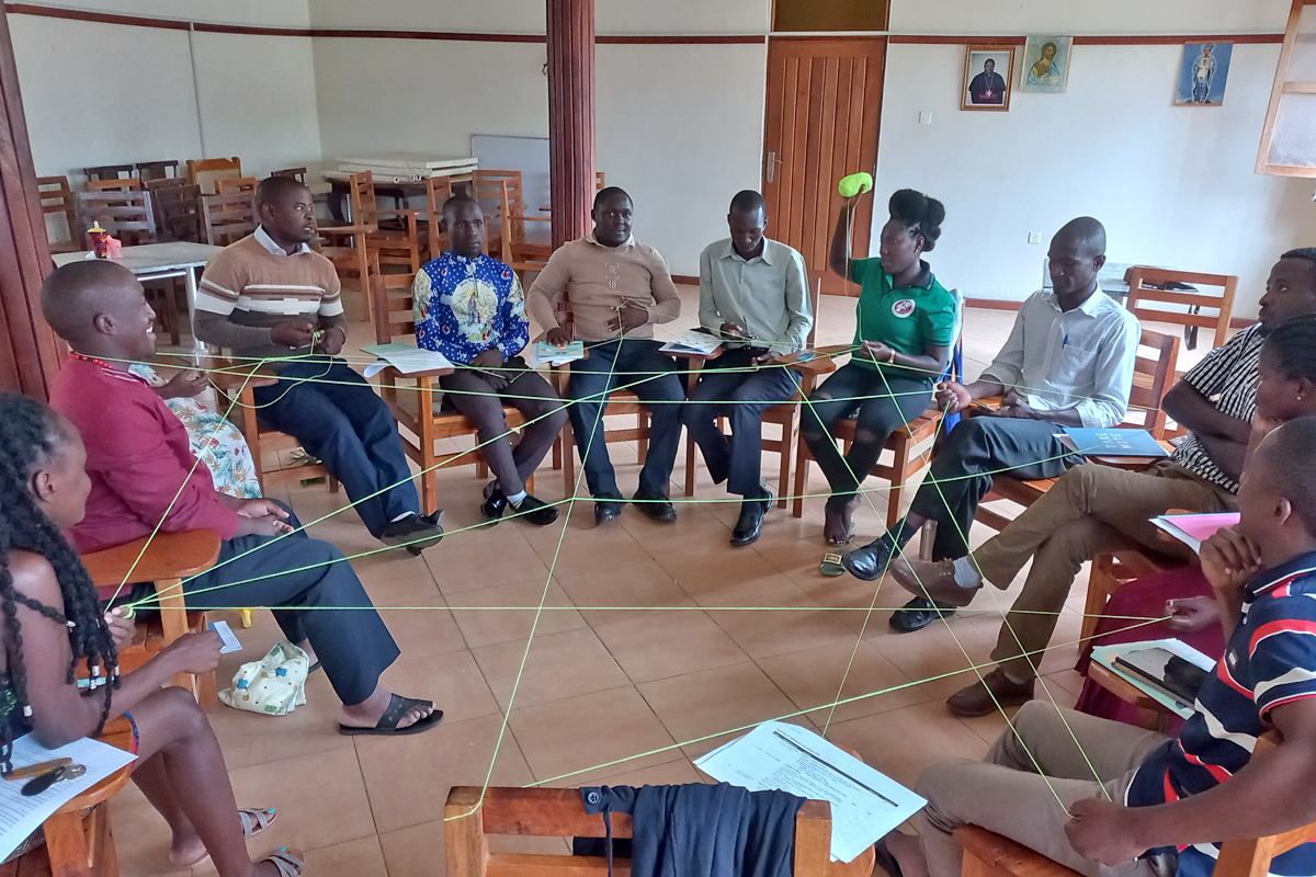 Im Team sind wir stärker. Die interaktive Übungen mit einem selbstgesponnenen Netz aus Wollfäden vermittelt den Teilnehmenden eines Jugendtrainings im August 2022 in Butende, wie wichtig Netzwerke für das Erreichen von Zielen sind.