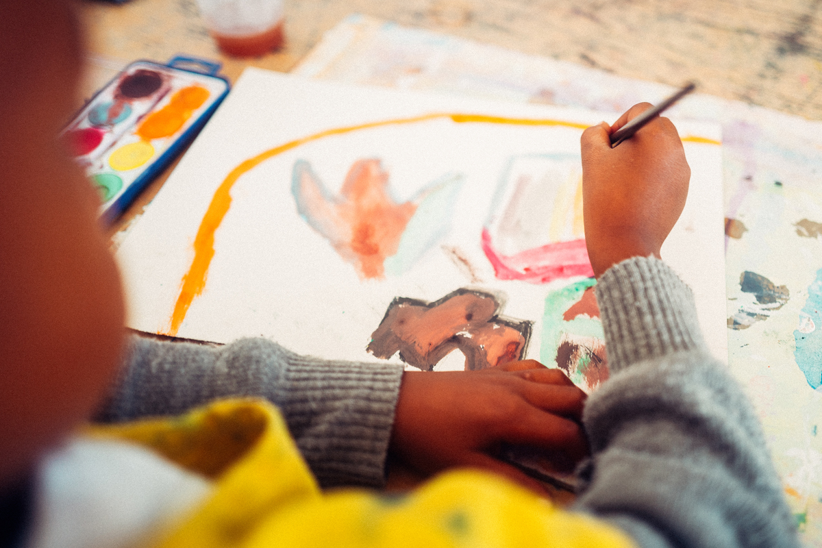 Ein Kind im Butterfly Art Project malt mit Wasserfarben. Diese Technik spricht die Gefühlswelt an und lässt die Kinder dabei tief ausatmen. Regelmäßiges Malen reduziert den toxischen Stress der Kinder und fördert ihre mentale Gesundheit.