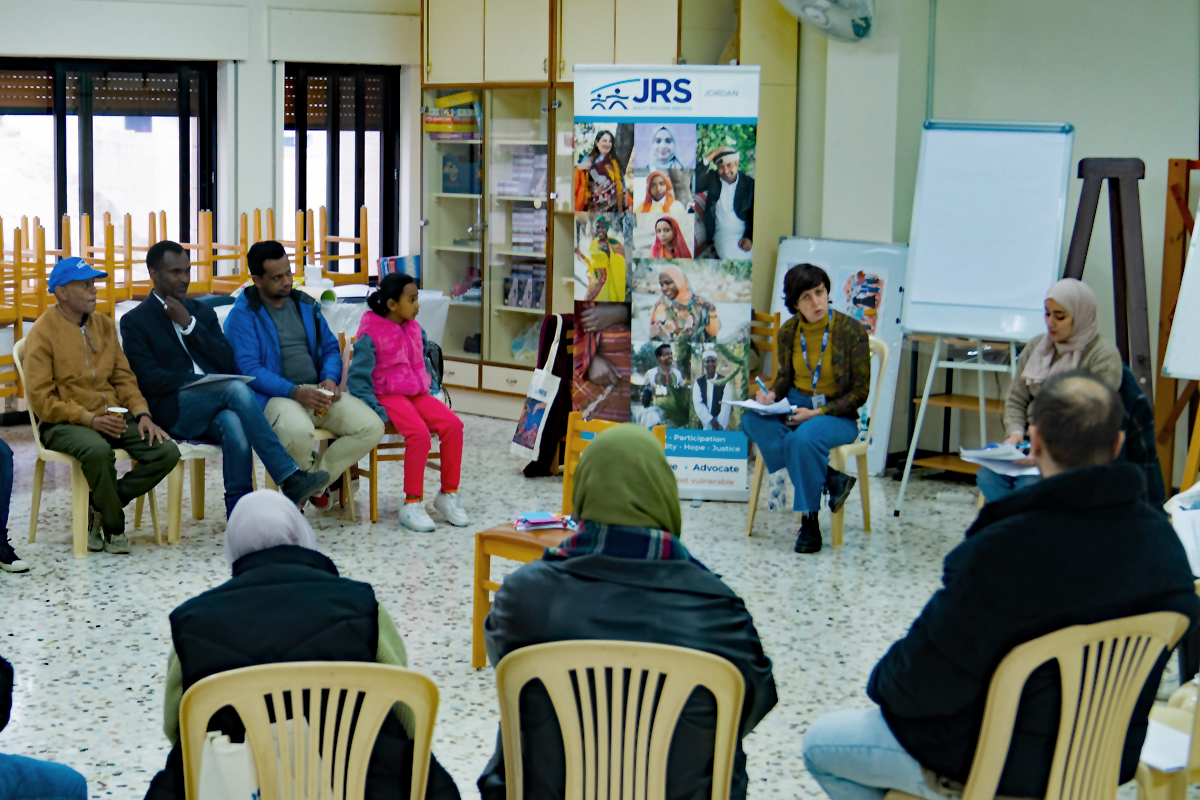 Mitglieder des JRS-Ausschusses und einer Gruppe von Vertretern von Flüchtlingsgemeinschaften diskutieren während einer Gemeindeberatung.