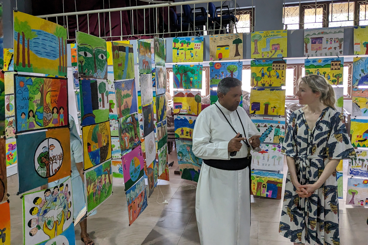 Father Rohan und Franziska Eder (von links) schauen sich die Ausstellung zu Religion und Umwelt mit Beiträgen von 400 Kindern aus der Region an. Sie ist vom CSR initiiert, um mittels interreligiösem Dialog Frieden zu fördern.  Die Veranstaltung findet jährlich mit wechselnden Themen statt und wird unter anderem von AGIAMONDO unterstützt.