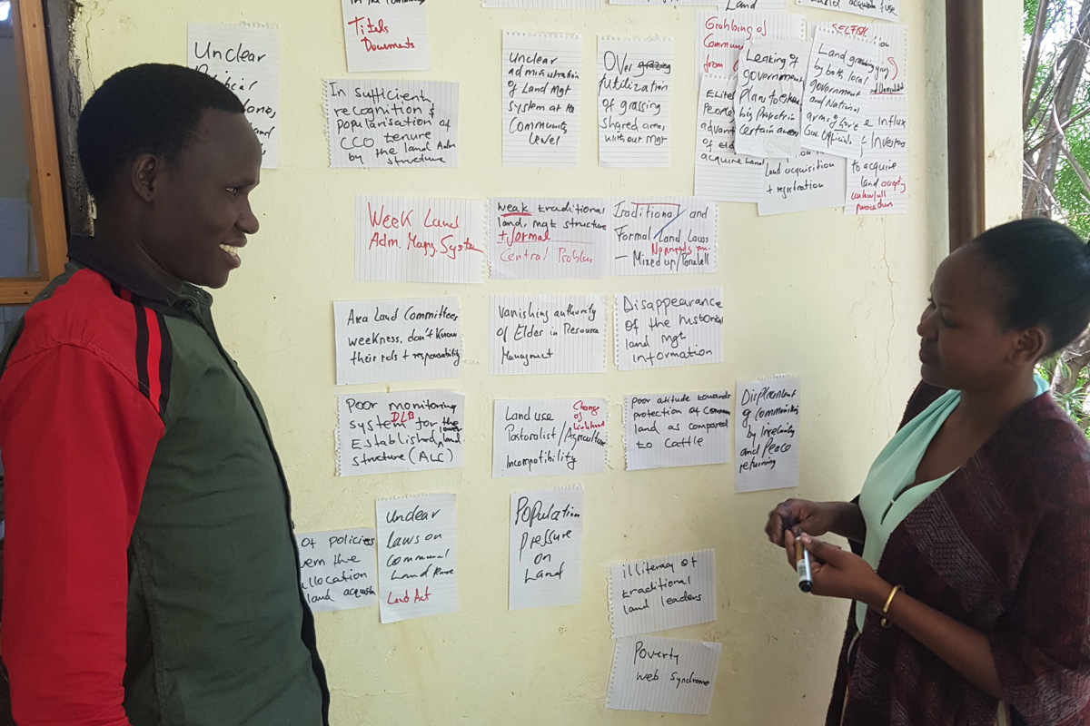 MitarbeiterInnen von der NGO Land Desk Moroto Frau und Mann sprechen über unrechtmäßige Aneignung von Land in Nord-Uganda