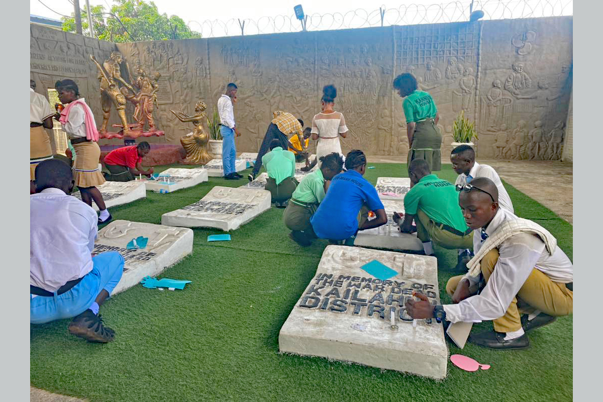 Jugendliche sind im Erinnerungsgarten bei den Grabsteinen