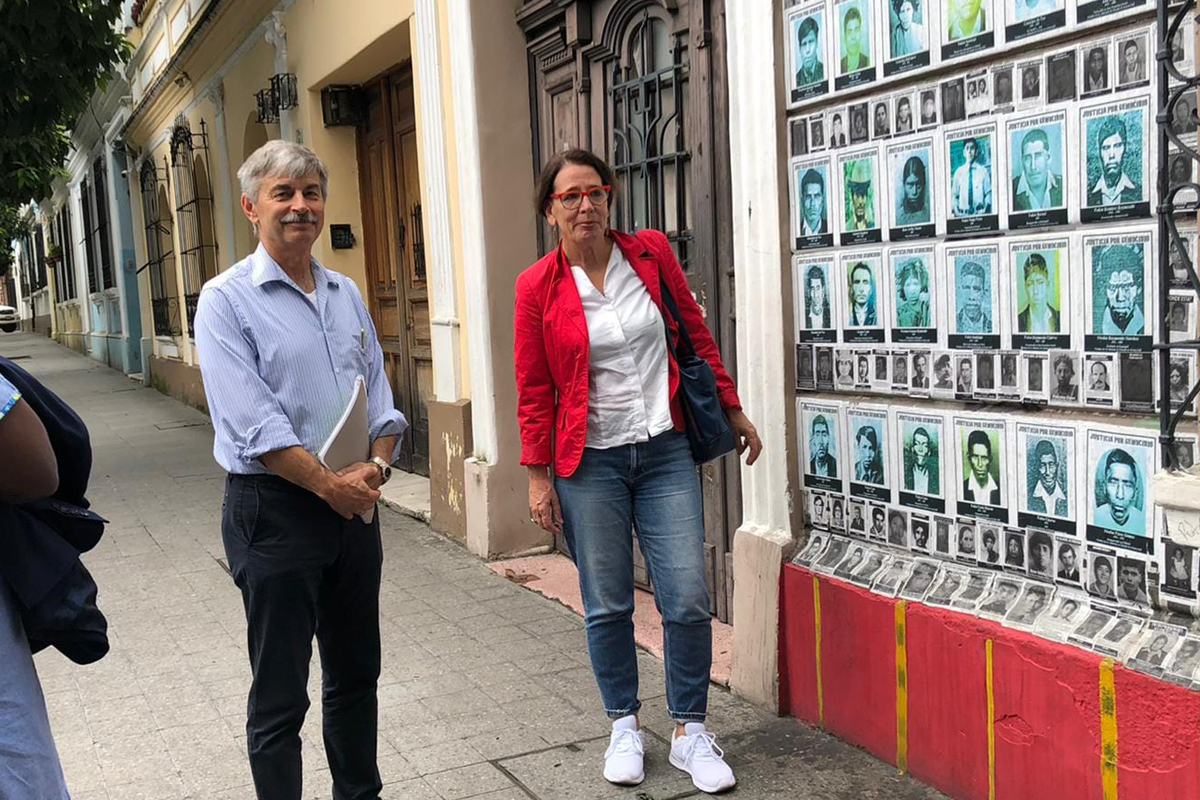 Stefan Pleisnitzer, der ZFD-Koordinator in Kolumbien und Martina Richard vor dem Gebäude der Partnerorganisation CALDH Ein Mann und eine Frau stehen vor einem haus mit Fotos an der Wand.