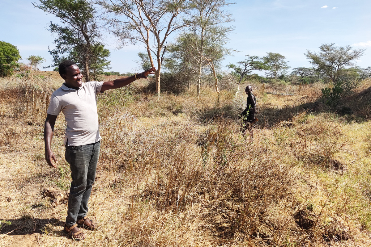 Faustine Langole erklärt etwas während er draußen in der landschaft steht.