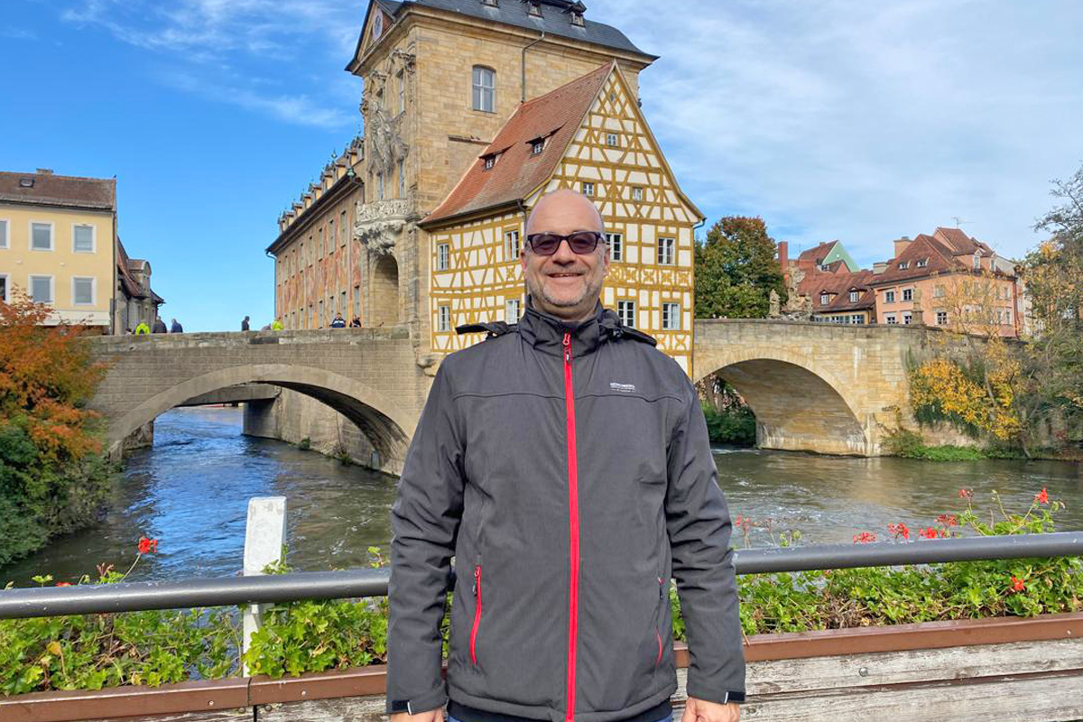 AGIAMONDO-Fachkraft Thomas Hirl mann vor Häusern und Fluss